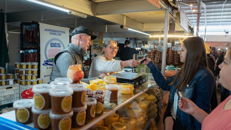 Clientes entregam cartão para pagamento aos expositores da feira da agricultura familiar.