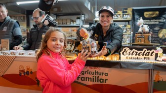 Expositora da agricultura familiar entrega cesta com produtos para menina