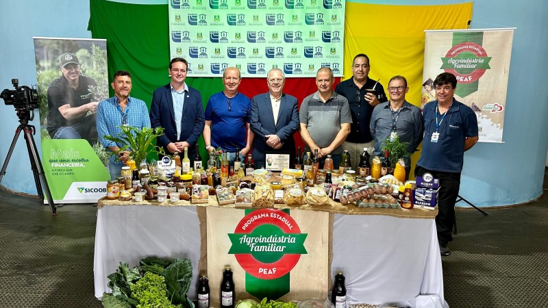 Secretário Covatti e autoridades posam em frente à mesa com produtos da agricultura familiar