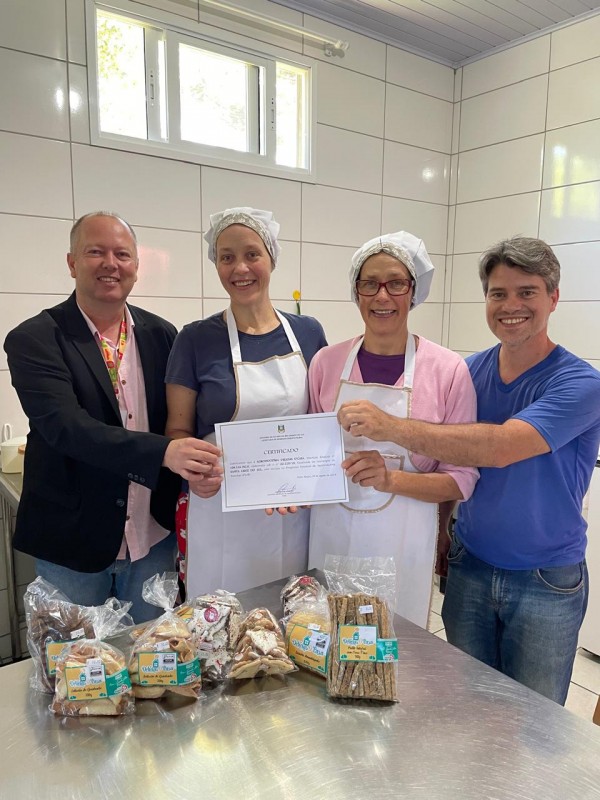 Quatro posam com o certificado do Peaf em frente à mesa com produtos da agricultura familiar.