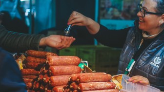 Mulher entrega salame ao cliente